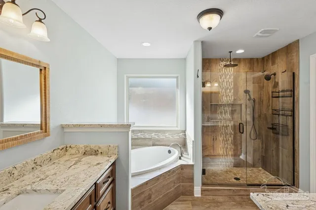 a bathroom with a granite countertop sink a bathtub and shower