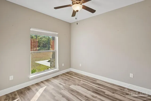 an empty room with a window and a ceiling fan
