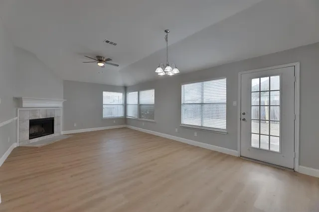 an empty room with windows and fireplace