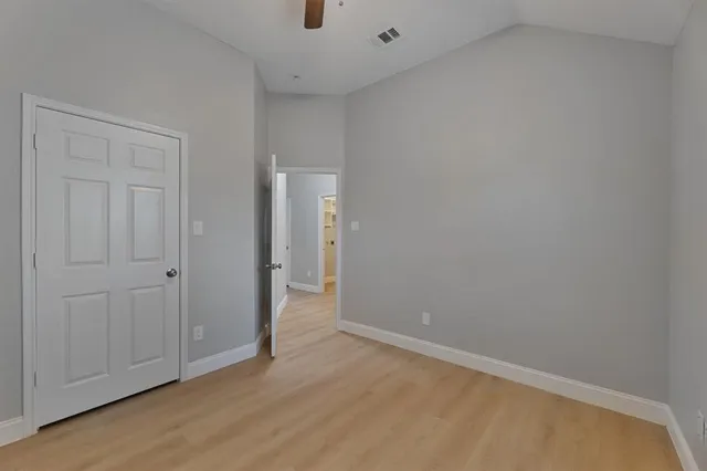 an empty room with ceiling fan and window