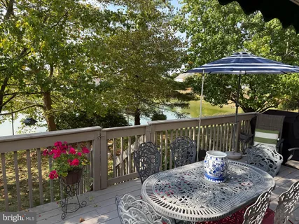a patio with wooden floor a yard a table and chairs
