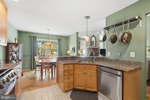 a kitchen with stainless steel appliances granite countertop a sink a stove and a wooden floors