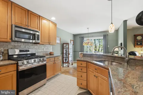 a kitchen with stainless steel appliances granite countertop a sink a stove top oven and cabinetry