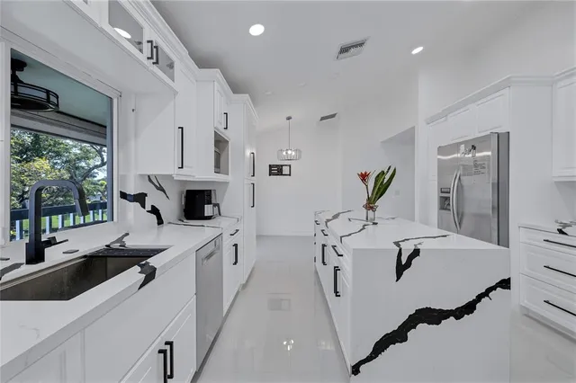 a spacious kitchen with stainless steel appliances a sink and a refrigerator