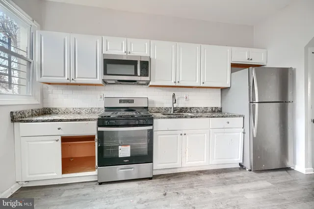 a kitchen with granite countertop white cabinets and stainless steel appliances