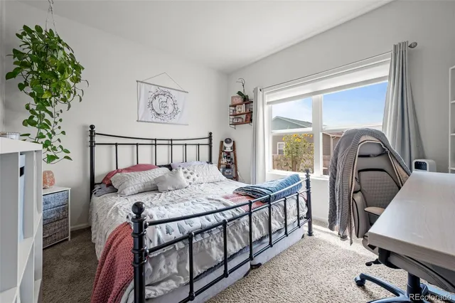a bedroom with a bed window and a potted plant on the table