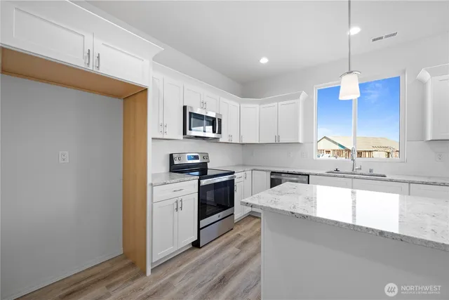 a kitchen with kitchen island a sink stainless steel appliances and cabinets