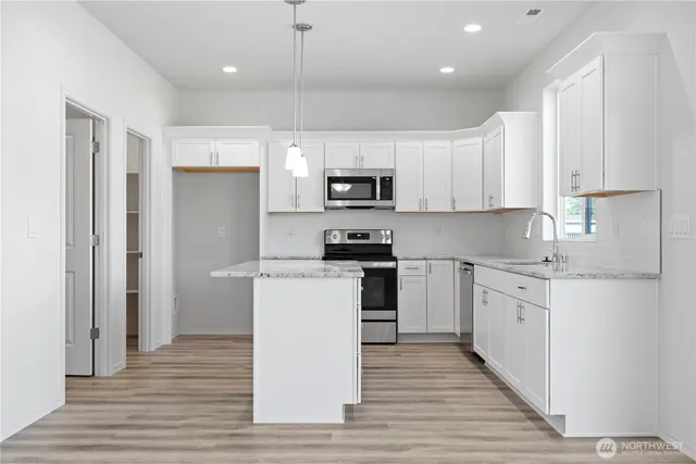 a kitchen with granite countertop a refrigerator stove top oven and sink