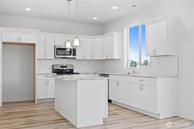 a kitchen with stainless steel appliances granite countertop a sink a stove a refrigerator and cabinets