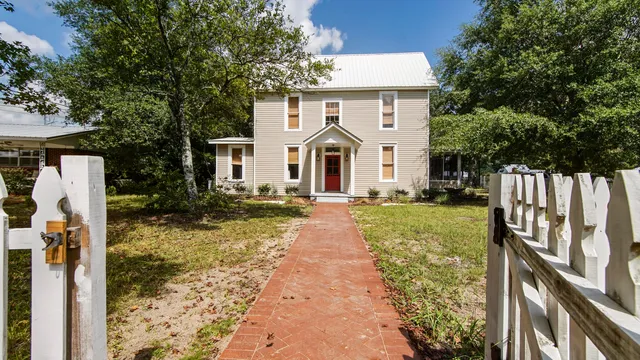 a view of a house with a small yard plants and large tree