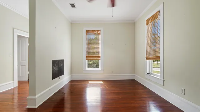 a view of an empty room with wooden floor and a window
