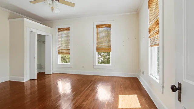 a view of an empty room with wooden floor and a window