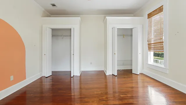 an empty room with wooden floor and windows