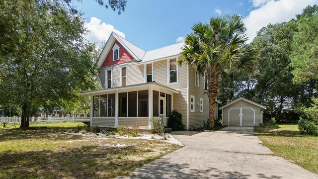 a view of a house with a yard and large tree