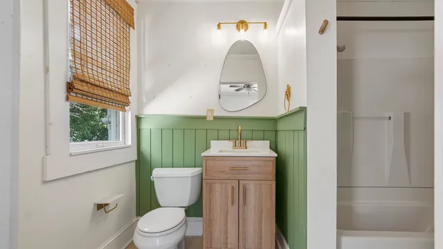 a bathroom with a toilet sink vanity and mirror