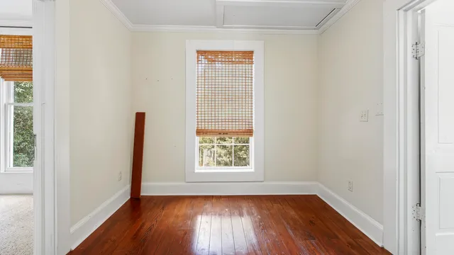a view of an empty room with wooden floor and a window