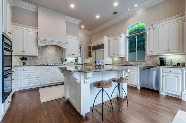 a kitchen with granite countertop white cabinets white appliances a sink and a window