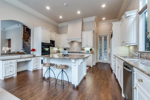 a open kitchen with stainless steel appliances granite countertop a stove top oven a sink dishwasher a dining table and chairs with wooden floor