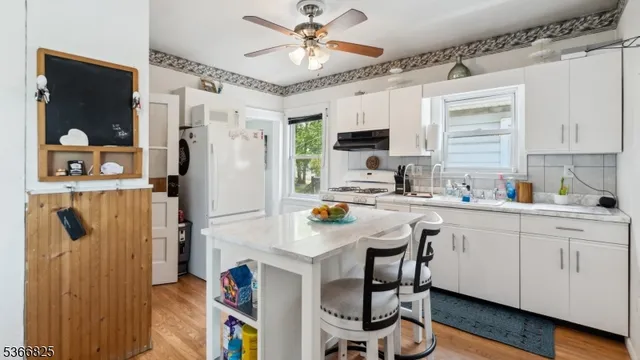 a kitchen with stainless steel appliances granite countertop a refrigerator a sink dishwasher a stove and a dining table with wooden floor