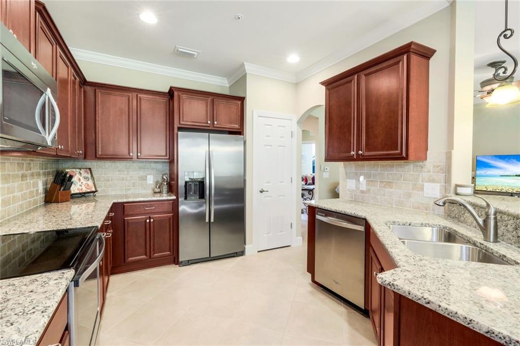 9532 Ironstone Terrace, Unit 102 Naples, FL 34120 - Photo 8 of 45 Kitchen with stainless steel appliances, arched walkways, light stone countertops, ornamental molding, and recessed lighting