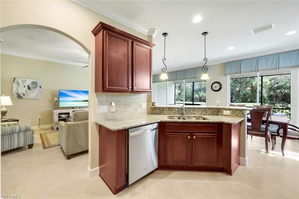 9532 Ironstone Terrace, Unit 102 Naples, FL 34120 - Photo 9 of 45 Kitchen with crown molding, stainless steel dishwasher, tasteful backsplash, light stone countertops, and arched walkways