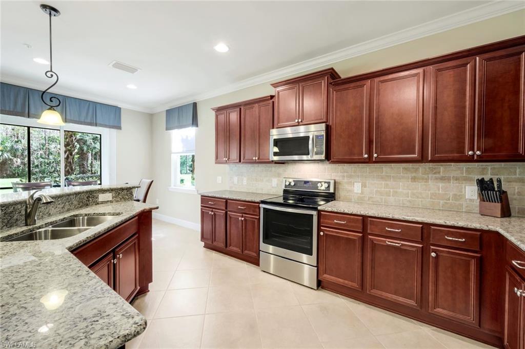 9532 Ironstone Terrace, Unit 102 Naples, FL 34120 - Photo 10 of 45 Kitchen featuring stainless steel appliances, ornamental molding, tasteful backsplash, hanging light fixtures, and light tile patterned flooring