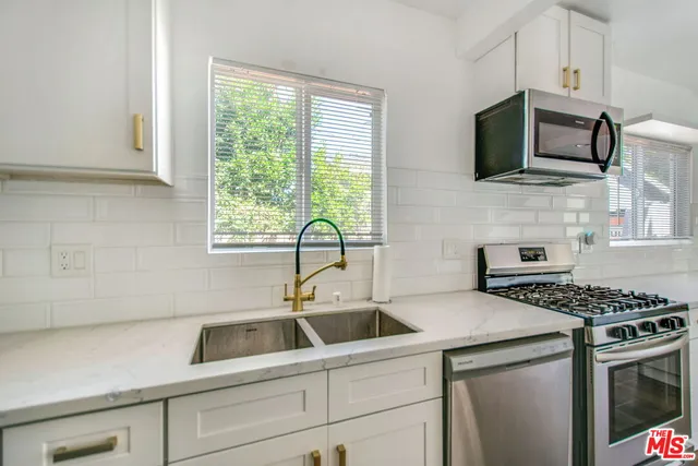 a kitchen with stainless steel appliances a sink a stove a microwave and wooden cabinets