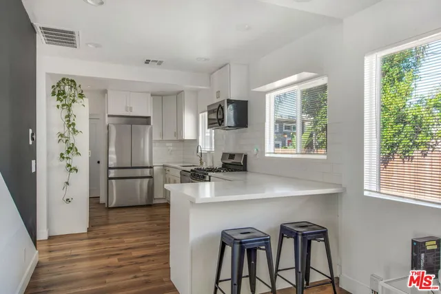 a kitchen with stainless steel appliances granite countertop a refrigerator a sink a stove a dining table and chairs