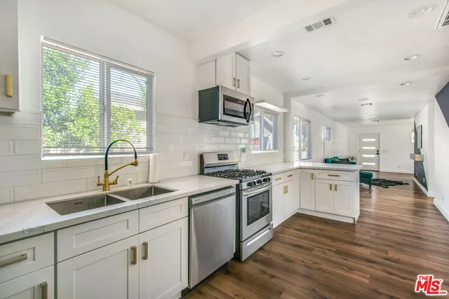 a kitchen with a sink wooden floor and stainless steel appliances
