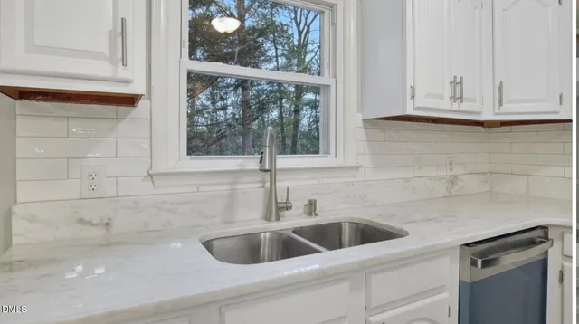 a kitchen with stainless steel appliances granite countertop a stove top oven a sink a refrigerator and white cabinets with wooden floor