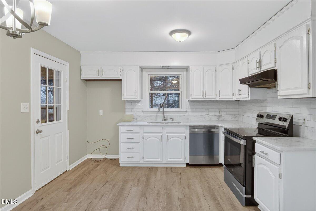 13013 Meadow Ridge Drive Rougemont, NC 27572 - Photo 7 of 27 a kitchen with stainless steel appliances granite countertop a stove top oven a sink a refrigerator and white cabinets with wooden floor
