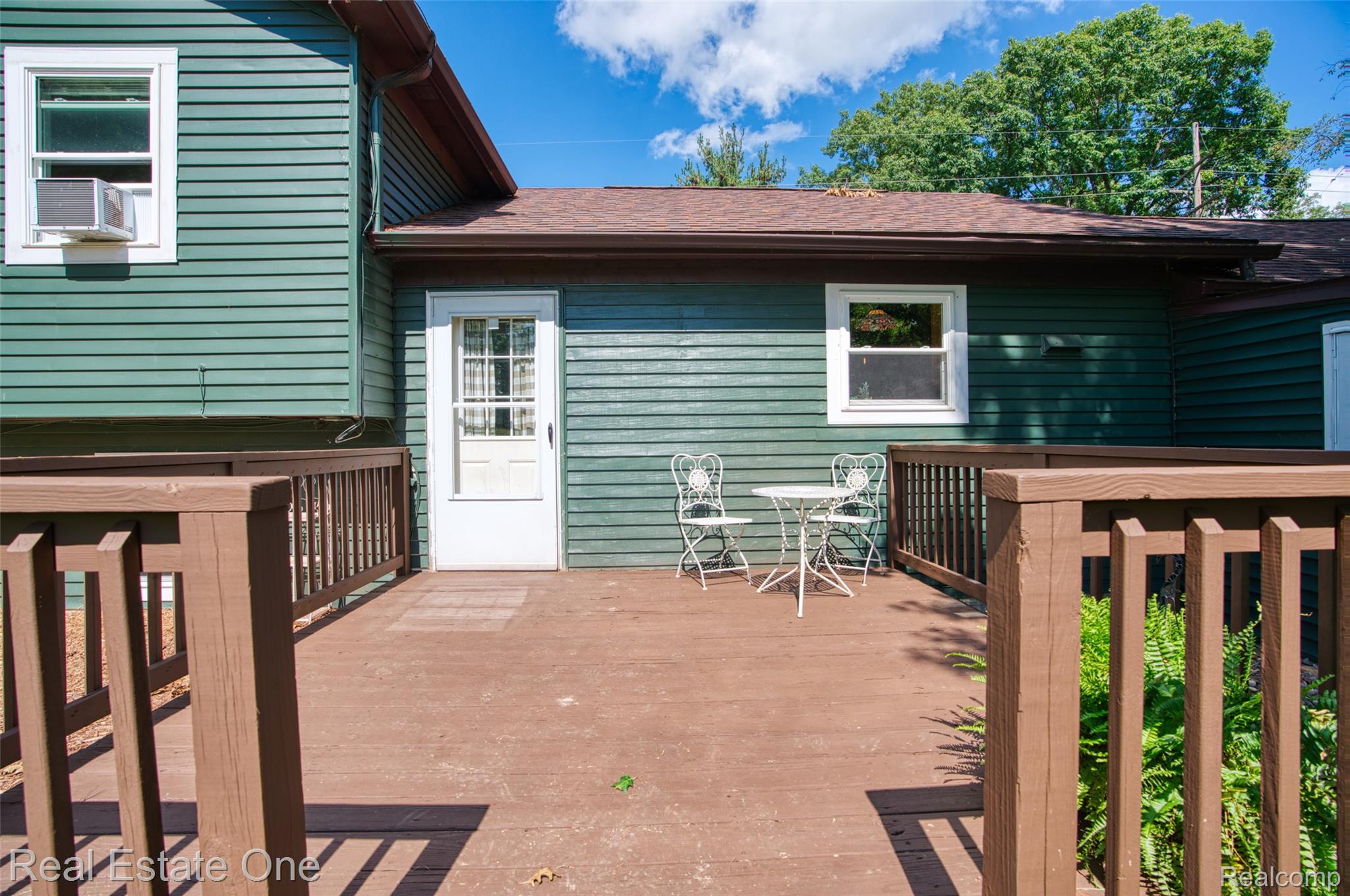 5130 Iosco Road Webberville, MI 48892 - Photo 30 of 39 Expansive wood deck with wood railings, green siding exterior, and white trim windows