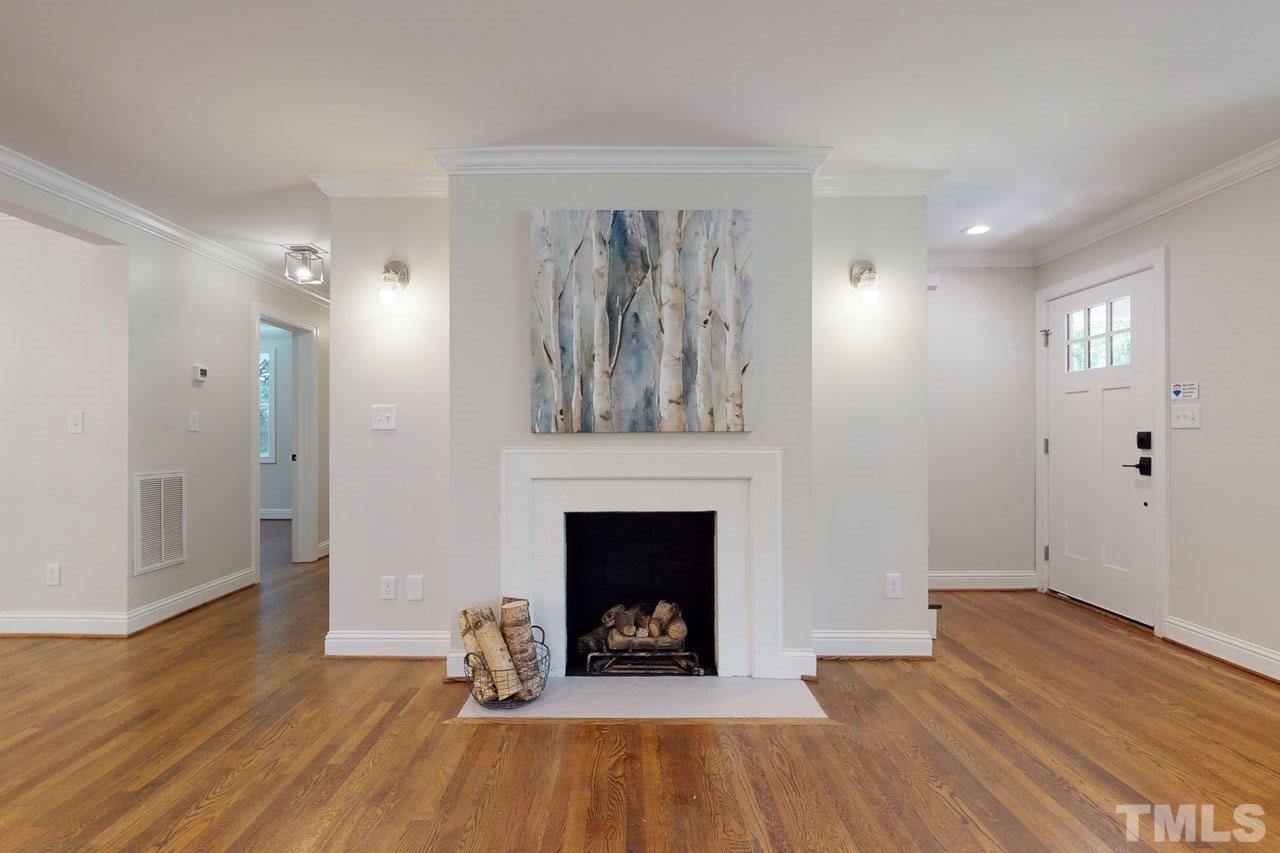 1304 Dixie Trail Raleigh, NC 27607 - Photo 7 of 26 an empty room with wooden floor fireplace and windows