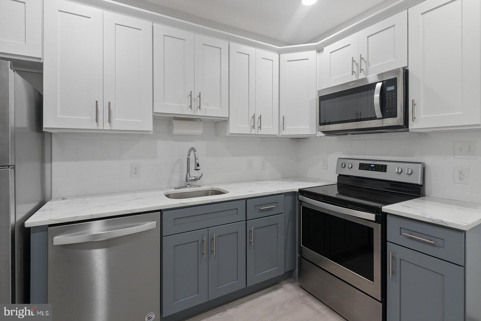5213 Rodman Street Philadelphia, PA 19143 - Photo 10 of 31 a kitchen with white cabinets and stainless steel appliances