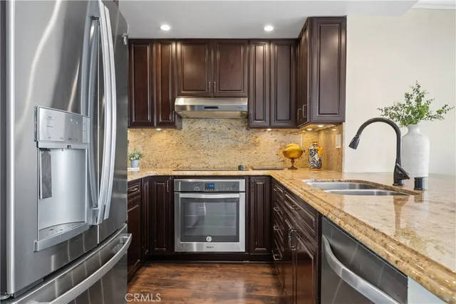 a kitchen with kitchen island granite countertop a stove sink and refrigerator
