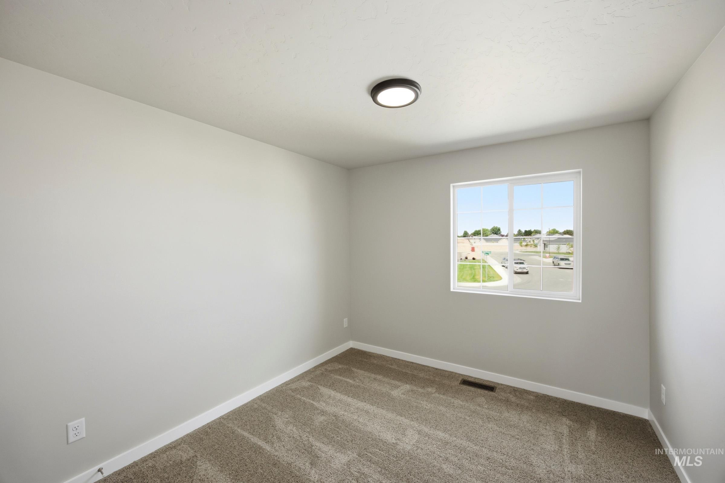 14044 Shiny Spruce Street Caldwell, ID 83607 - Photo 21 of 24 Neutral-toned room with a large window, carpeted flooring, white trim, and a contemporary flush-mount ceiling light
