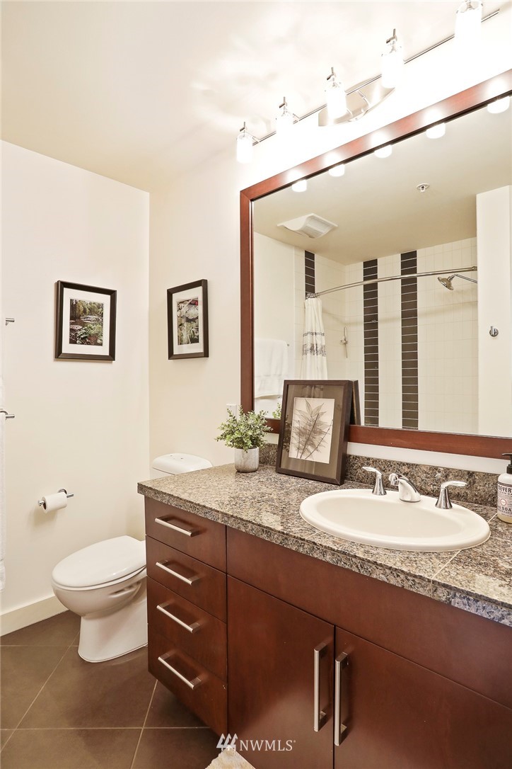 910 Lenora Street, Unit S1203 Seattle, WA 98121 - Photo 19 of 39 a bathroom with a granite countertop sink a toilet and mirror