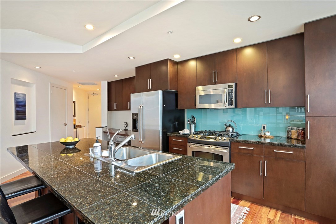 910 Lenora Street, Unit S1203 Seattle, WA 98121 - Photo 7 of 39 a kitchen with stainless steel appliances granite countertop a sink and a refrigerator