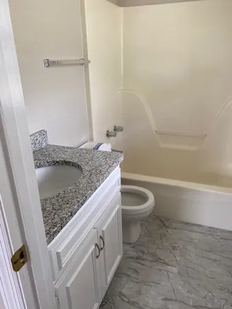 a bathroom with a granite countertop sink a toilet and bathtub