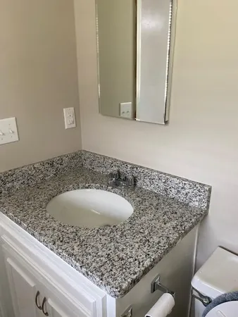 a bathroom with a granite countertop sink and a mirror