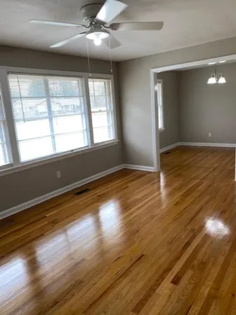 a view of an empty room with wooden floor and a window