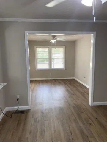 a view of an empty room with wooden floor and a window