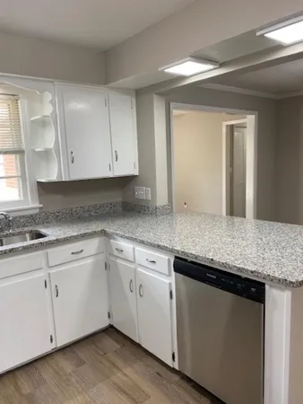 a kitchen with granite countertop white cabinets and a sink