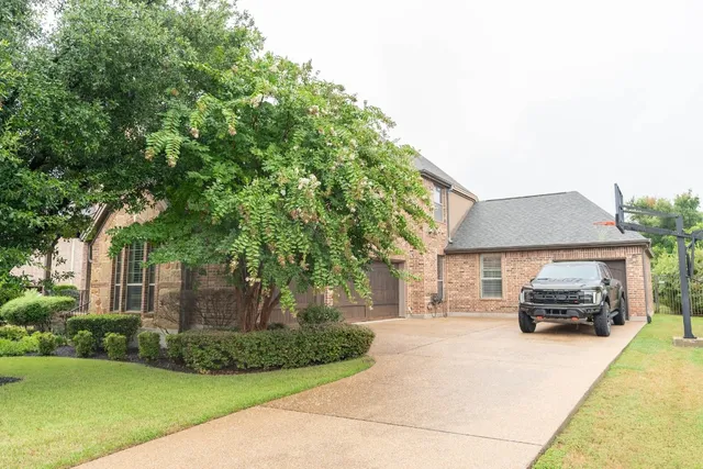 a car parked in front of a brick house with potted plants