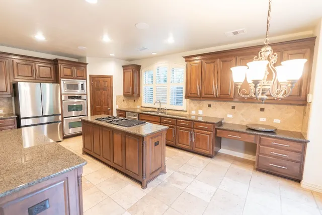 a kitchen with stainless steel appliances granite countertop a stove a sink and a refrigerator