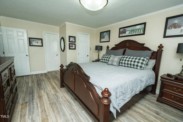 a spacious bedroom with a bed and wooden floor