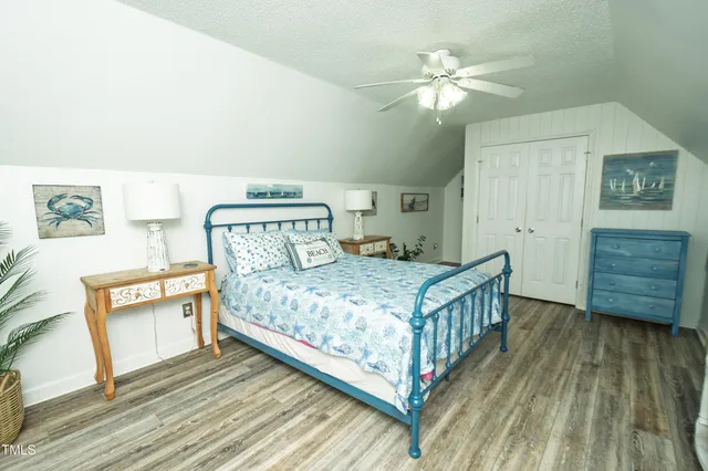 a bedroom with a bed a dresser with wooden floor