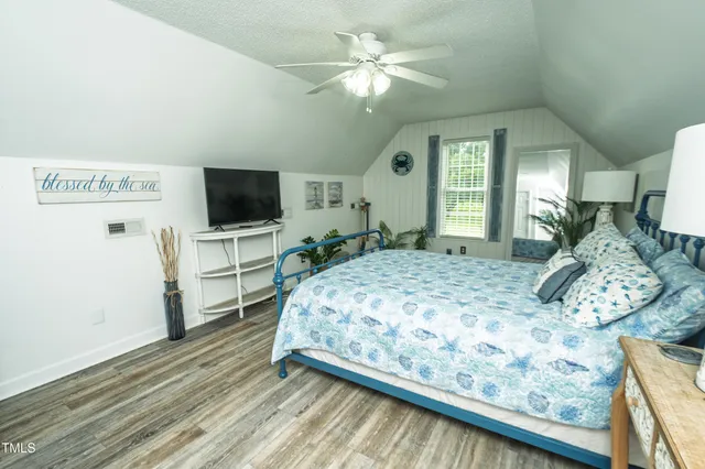 a bedroom with a large bed and a flat tv screen on dresser