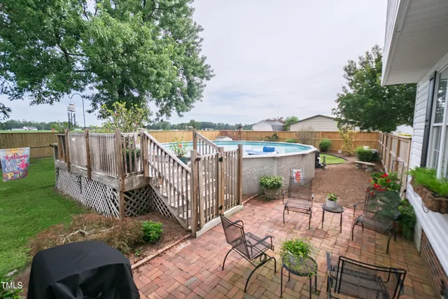a view of a patio with table and chairs potted plants with wooden floor and fence