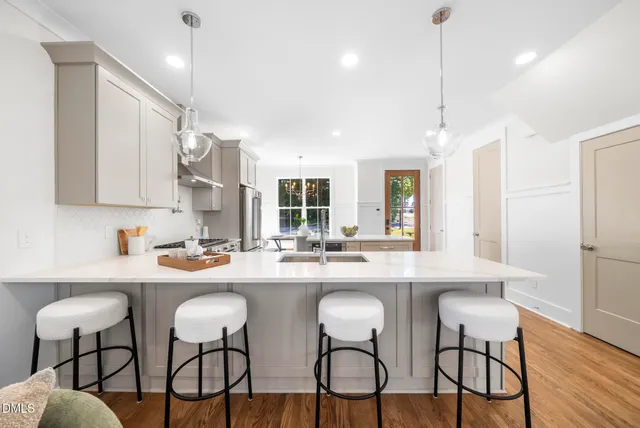 a kitchen with stainless steel appliances a dining table chairs and wooden floor